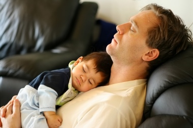 father and son asleep on a leather couch