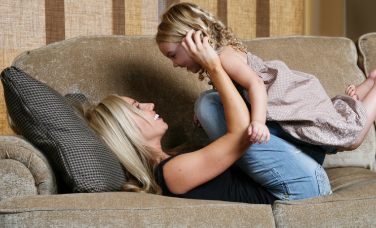 mother and daughter playing on couch
